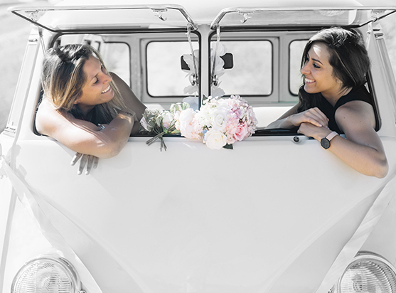 Zwei Brautjungfern in weisem, alten VW Bus